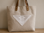 Front view of a neutral tote bag decorated with the handmade white triangular crochet lace motif