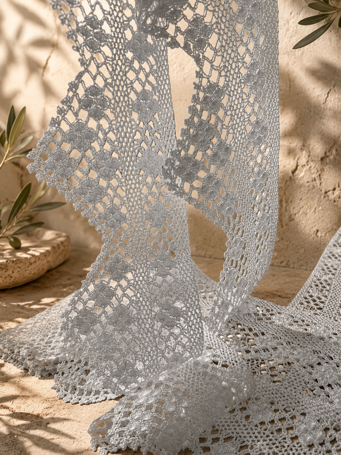 Close view of the white crochet lace border pieces draped vertically to show their pointed edging and handmade texture.