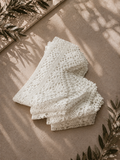 Folded view of the handmade white crochet lace border set styled on a neutral surface with soft shadows.