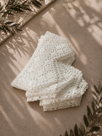 Folded view of the handmade white crochet lace border set styled on a neutral surface with soft shadows.