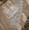 White handmade crochet lace edge set arranged on a warm neutral textile, showing the stepped upper profiles and pointed lower edging.