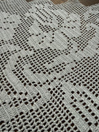 Close-up of the handmade white crochet lace showing the geometric stitch structure and pointed edge detail.