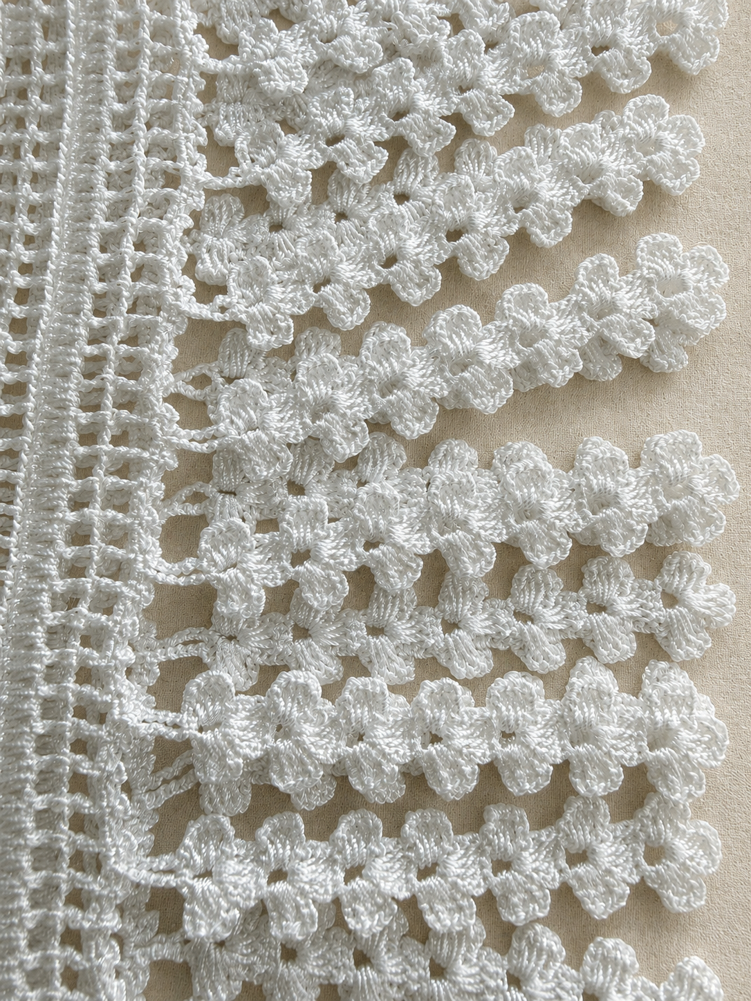 Close-up of the hand-finished white crochet fringe along the lace panel edge