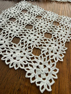 Close-up of the white crochet lace showing the joined motifs, open spaces and detailed decorative edge construction.