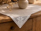 Styling example showing the triangular white crochet lace motif placed at the corner of a neutral table textile.