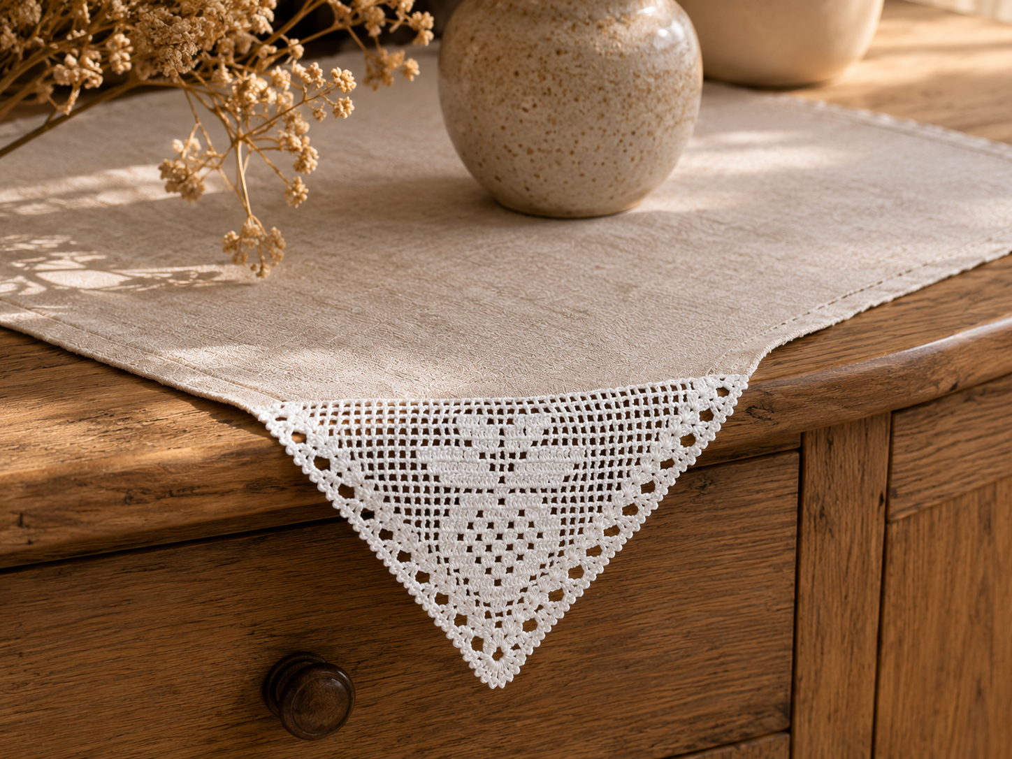 Styling example showing the triangular white crochet lace motif placed at the corner of a neutral table textile.