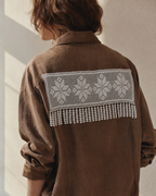 White floral crochet lace panel styled across the back of a brown blouse