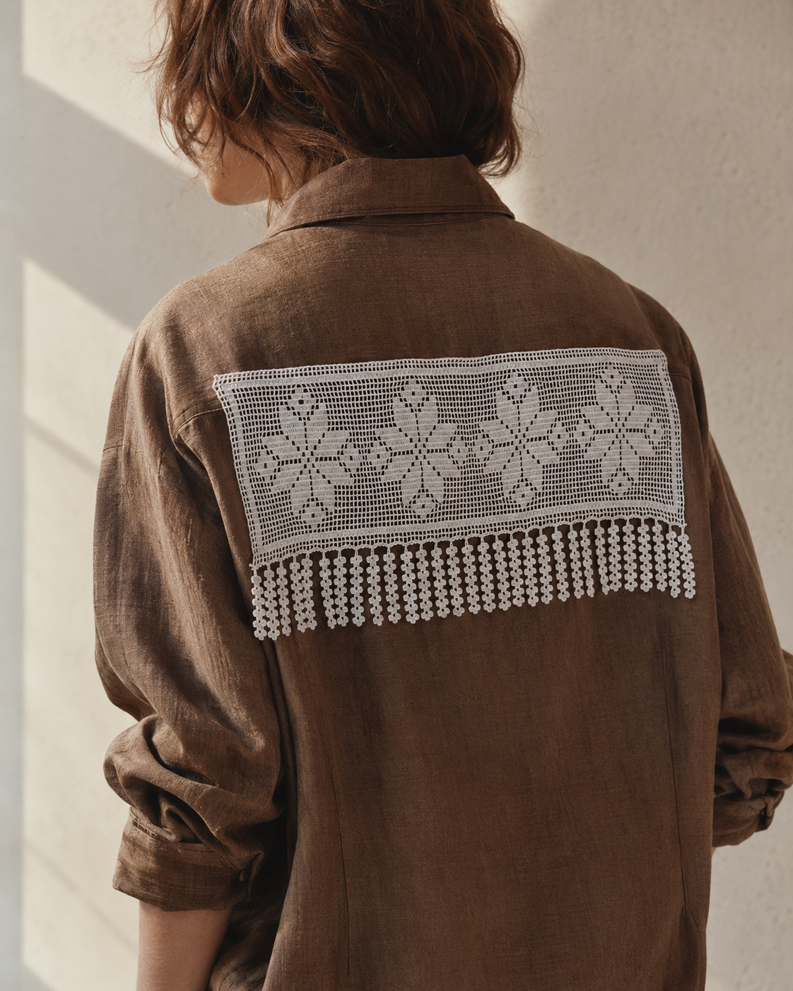 White floral crochet lace panel styled across the back of a brown blouse