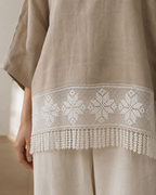 White floral crochet lace panel with fringe styled along the hem of a neutral garment
