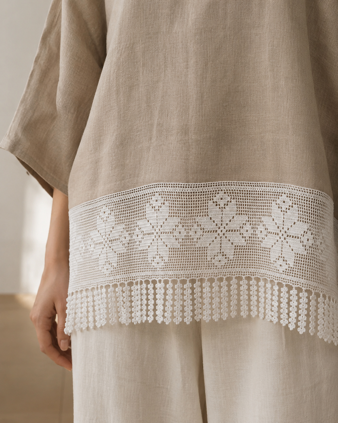 White floral crochet lace panel with fringe styled along the hem of a neutral garment