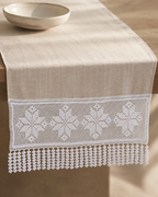 White floral crochet lace panel used as a decorative detail on a linen-covered table