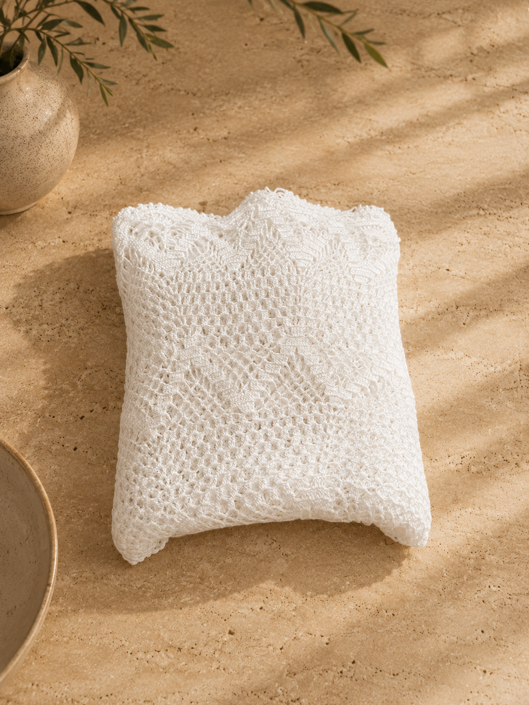 Handmade white crochet lace table topper folded into a compact square for storage.