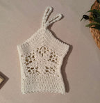 Angled flat-lay view of the white cotton crochet top highlighting the floral motif construction, straps and open lacework.