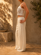 Side view of the white cotton crochet lace top showing its slim straps, openwork texture and cropped hem.