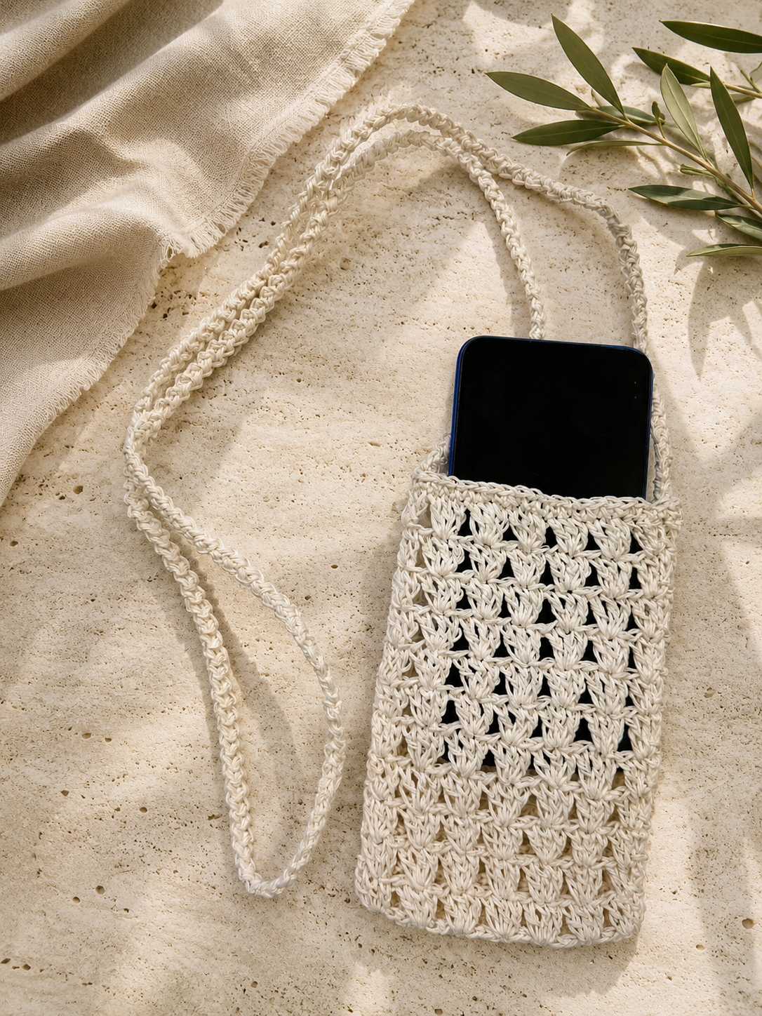 Black smartphone placed inside the white handmade crochet phone bag.