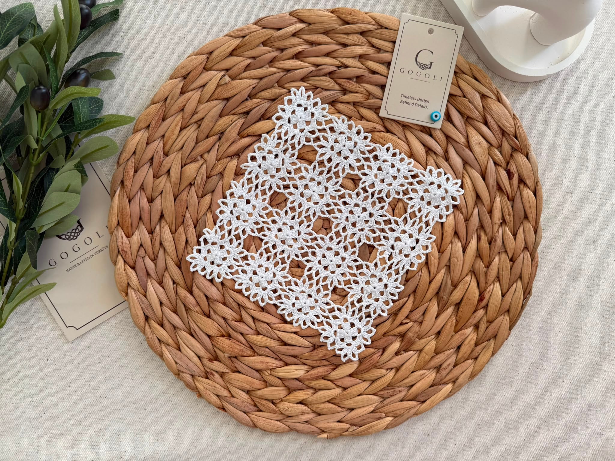 Close view of a handmade white crochet table-linen piece showing the repeating floral motifs, joined openwork and decorative edges.