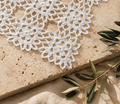 A close-up view of this handmade white crochet motif shows repeating floral patterns, joined openwork, and decorative edges.