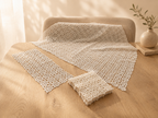 Styled arrangement of the white crochet table-linen set showing the large square topper, rectangular piece and folded small doilies.