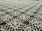 Macro view of the handmade white crochet surface showing repeated motifs, joining points and fine thread texture.