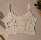 Flat-lay front view of the white crochet crop top showing two large floral motifs, V-neckline and decorative crochet hem.