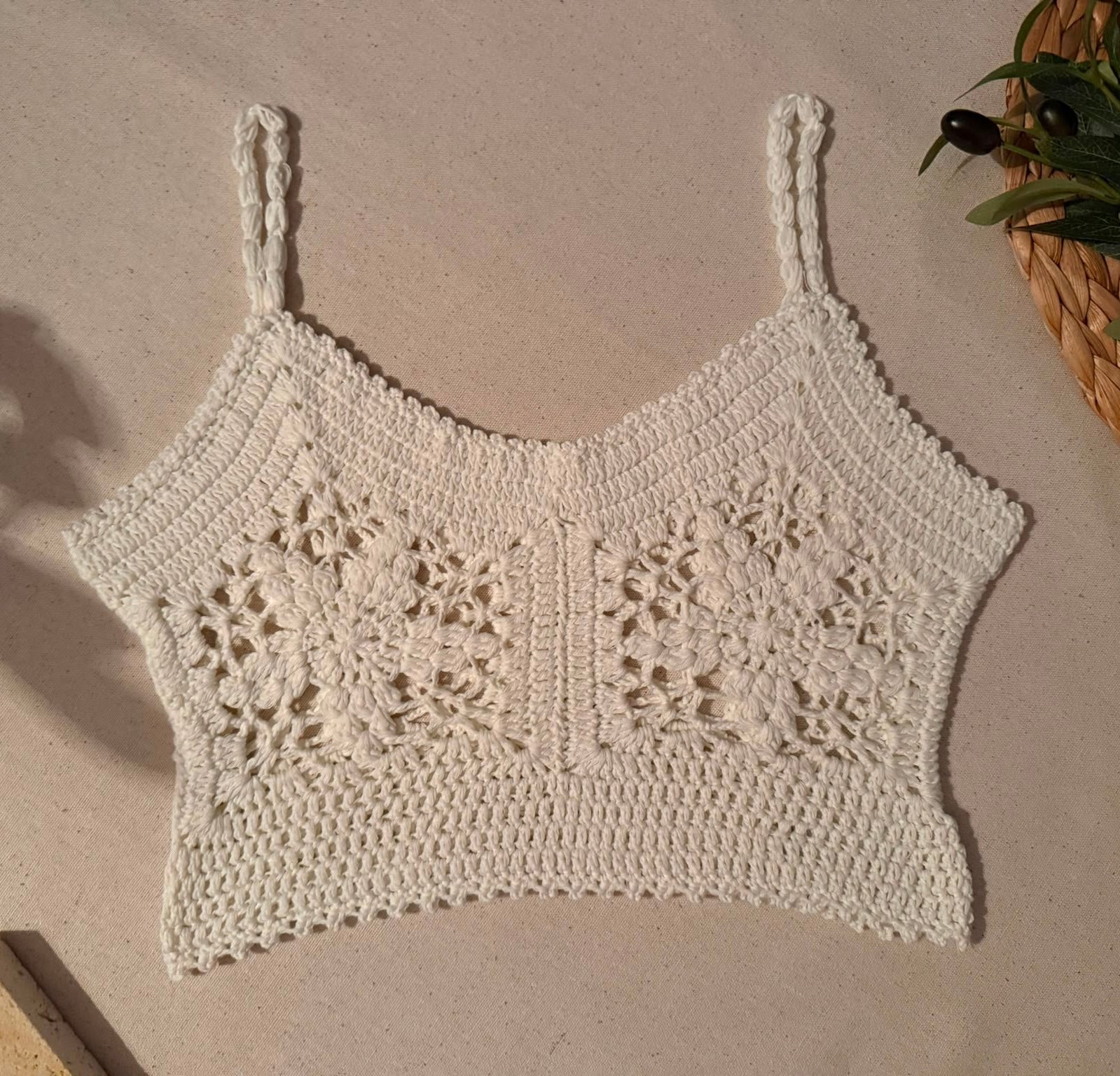 Flat-lay front view of the white crochet crop top showing two large floral motifs, V-neckline and decorative crochet hem.