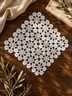 Flat-lay view of a square white crochet doily showing the symmetrical floral and circular motif arrangement.