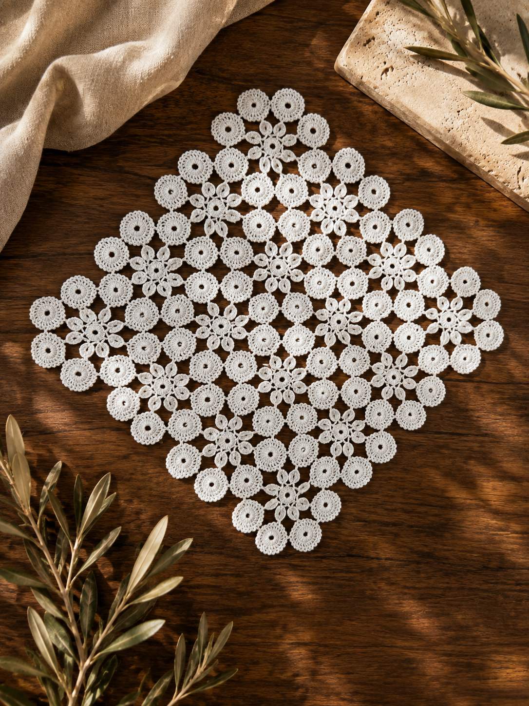 Flat-lay view of a square white crochet doily showing the symmetrical floral and circular motif arrangement.