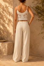 Back view of the handmade white floral crochet top showing its openwork construction, narrow straps and cropped length.