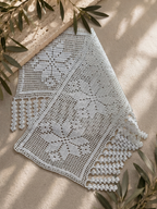 Angled view of the white floral filet crochet lace panel and decorative fringe