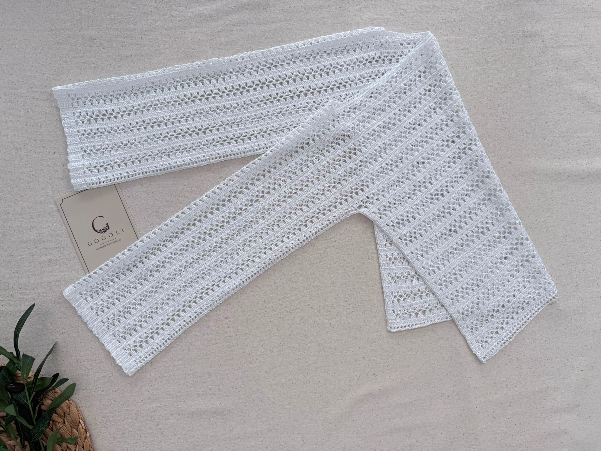 Full flat-lay view of the white crochet blouse showing its geometric T-shaped construction, boat neckline and right-angle underarms