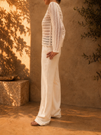 Back view of the bright-white crochet blouse showing the repeating openwork rows across the body and long sleeves.