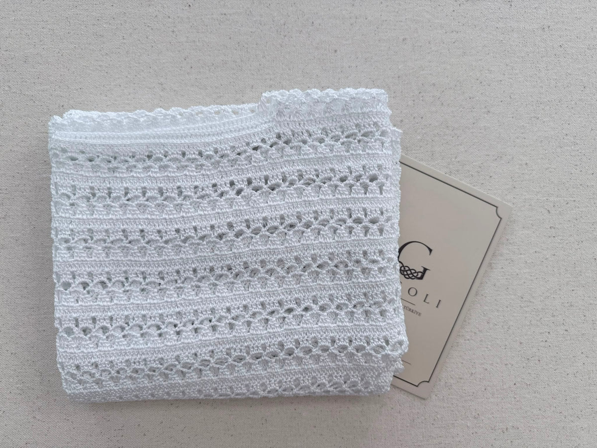 Folded view of the bright-white crochet blouse highlighting its repeating openwork rows and defined polyester stitches.
