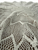 Close-up of the white crochet lace pattern extending from the centre toward the decorative outer border.