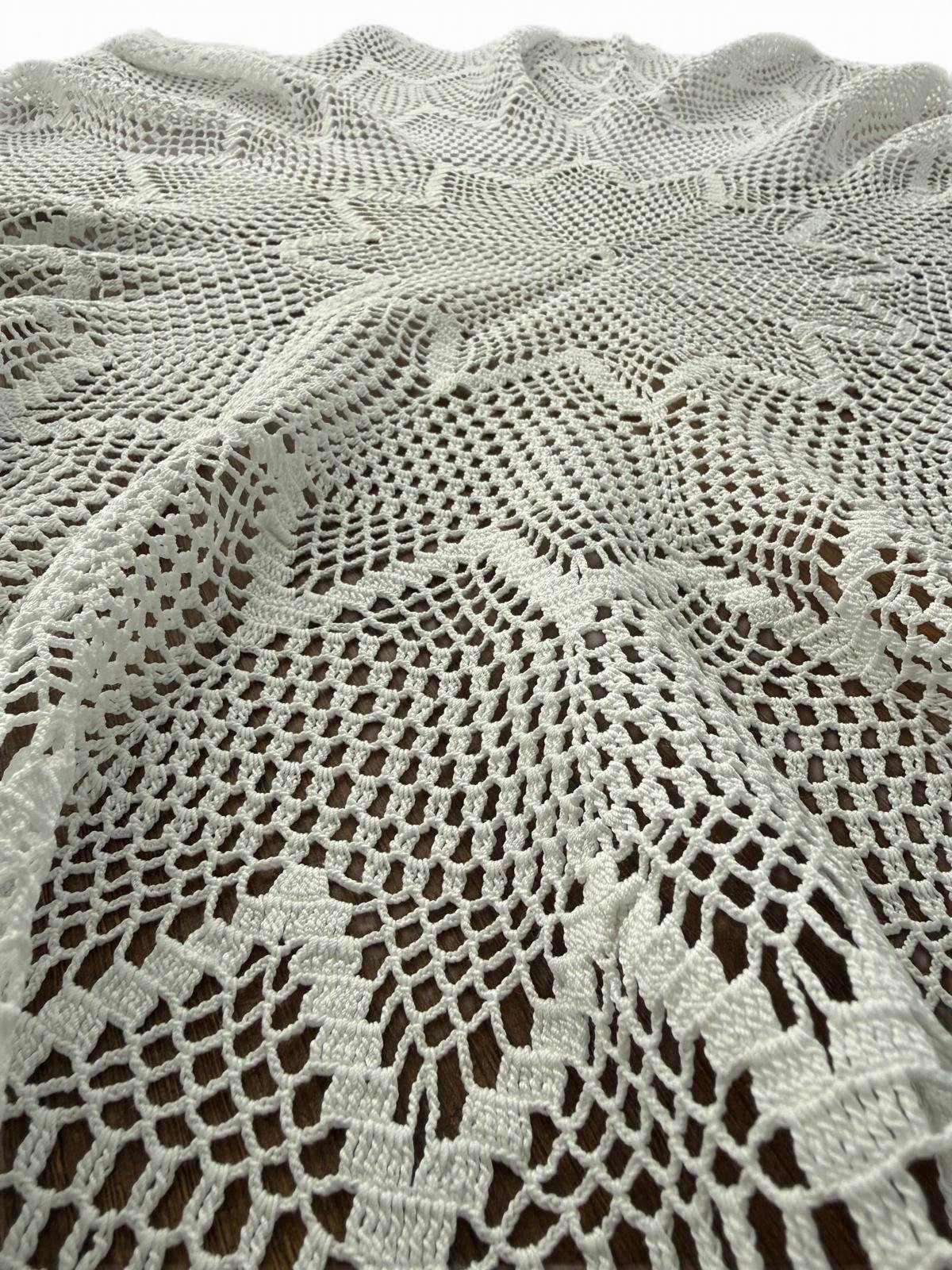 Close-up of the white crochet lace pattern extending from the centre toward the decorative outer border.